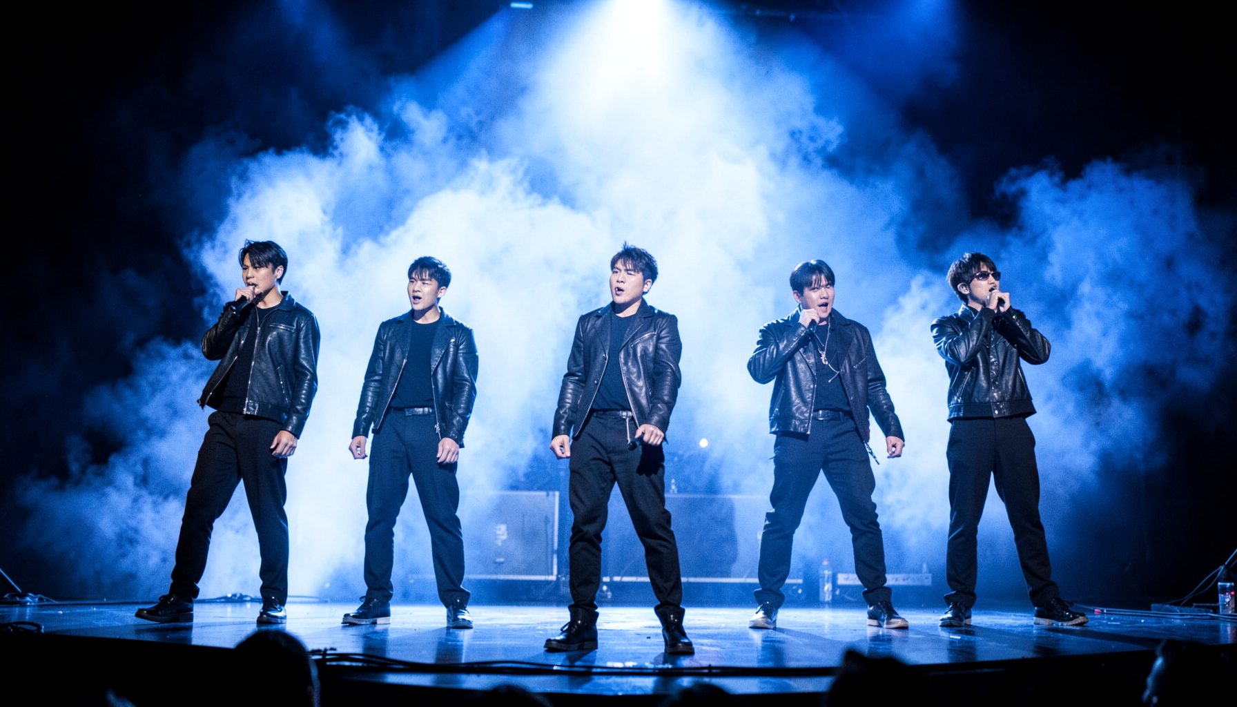 EXO performing on a large stage with dramatic blue and white lighting in coordinated dark outfits