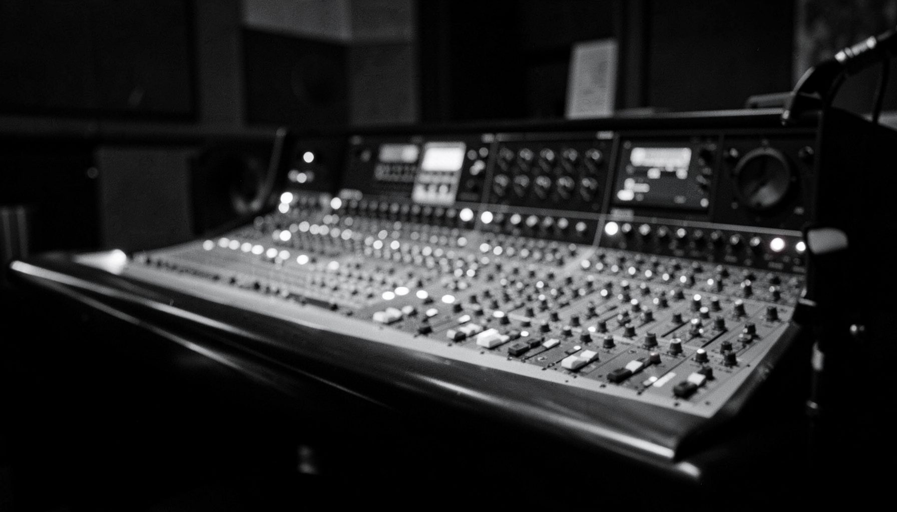 Moody black-and-white image of a recording studio console with soft glow, cinematic and dramatic